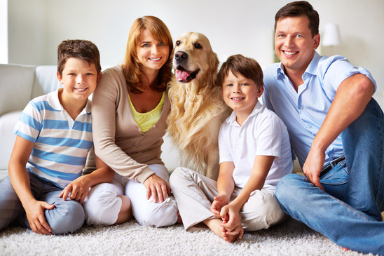 Portrait of happy father, mother and kids with fluffy Labrador looking at camera